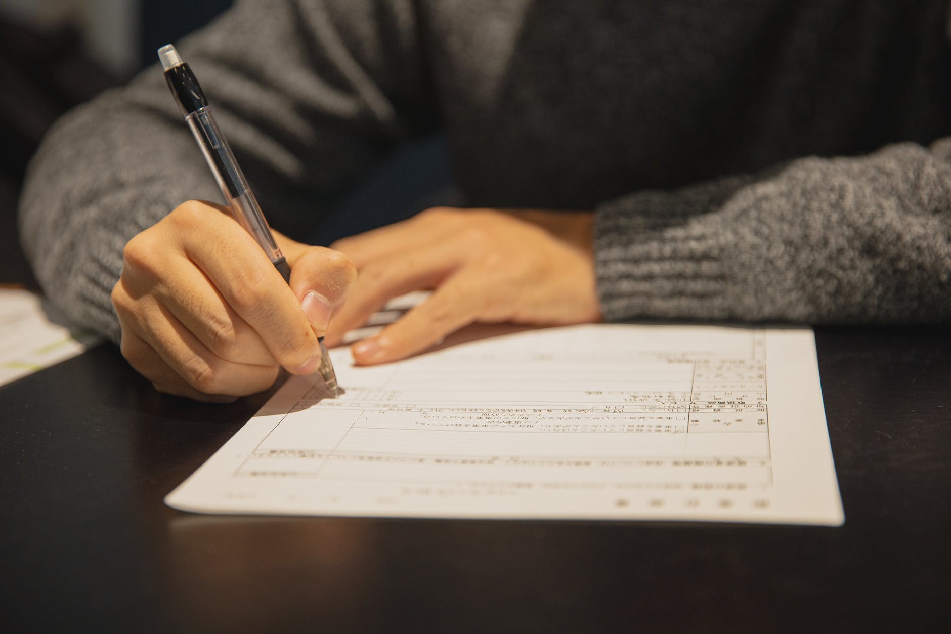 man filling in form on parer at table